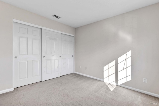 unfurnished bedroom with light carpet and a closet