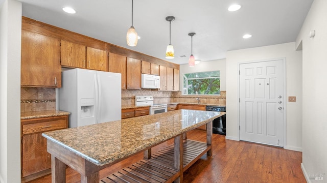 kitchen with white appliances, brown cabinetry, dark wood-type flooring, a kitchen bar, and tasteful backsplash