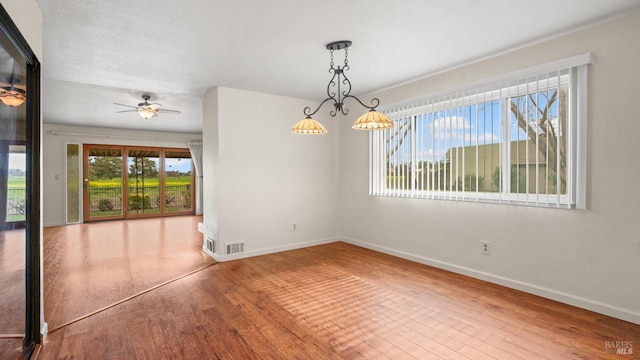 spare room with visible vents, a ceiling fan, baseboards, and hardwood / wood-style flooring