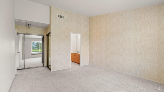 spare room featuring light carpet, visible vents, and wallpapered walls