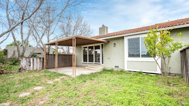 back of house featuring fence, stucco siding, a lawn, a chimney, and a patio area