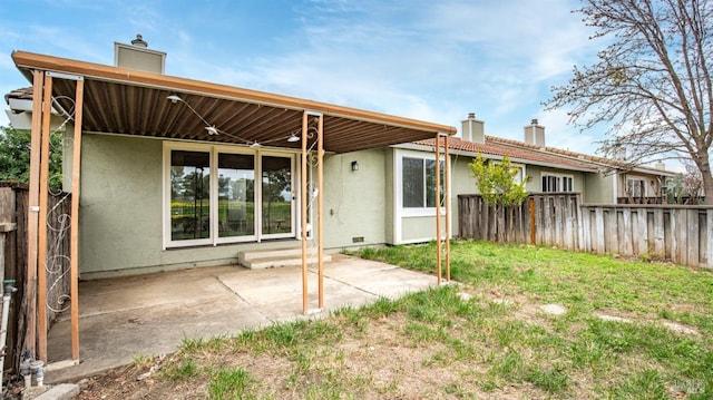 back of property with a patio area, stucco siding, fence, and a chimney