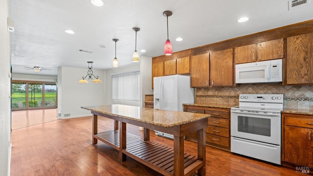 kitchen with brown cabinetry, visible vents, white appliances, and tasteful backsplash