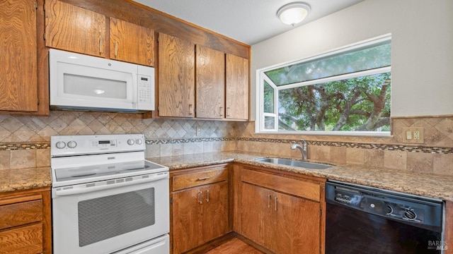 kitchen with a sink, white appliances, backsplash, and brown cabinets