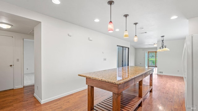 kitchen featuring light wood finished floors, freestanding refrigerator, and baseboards