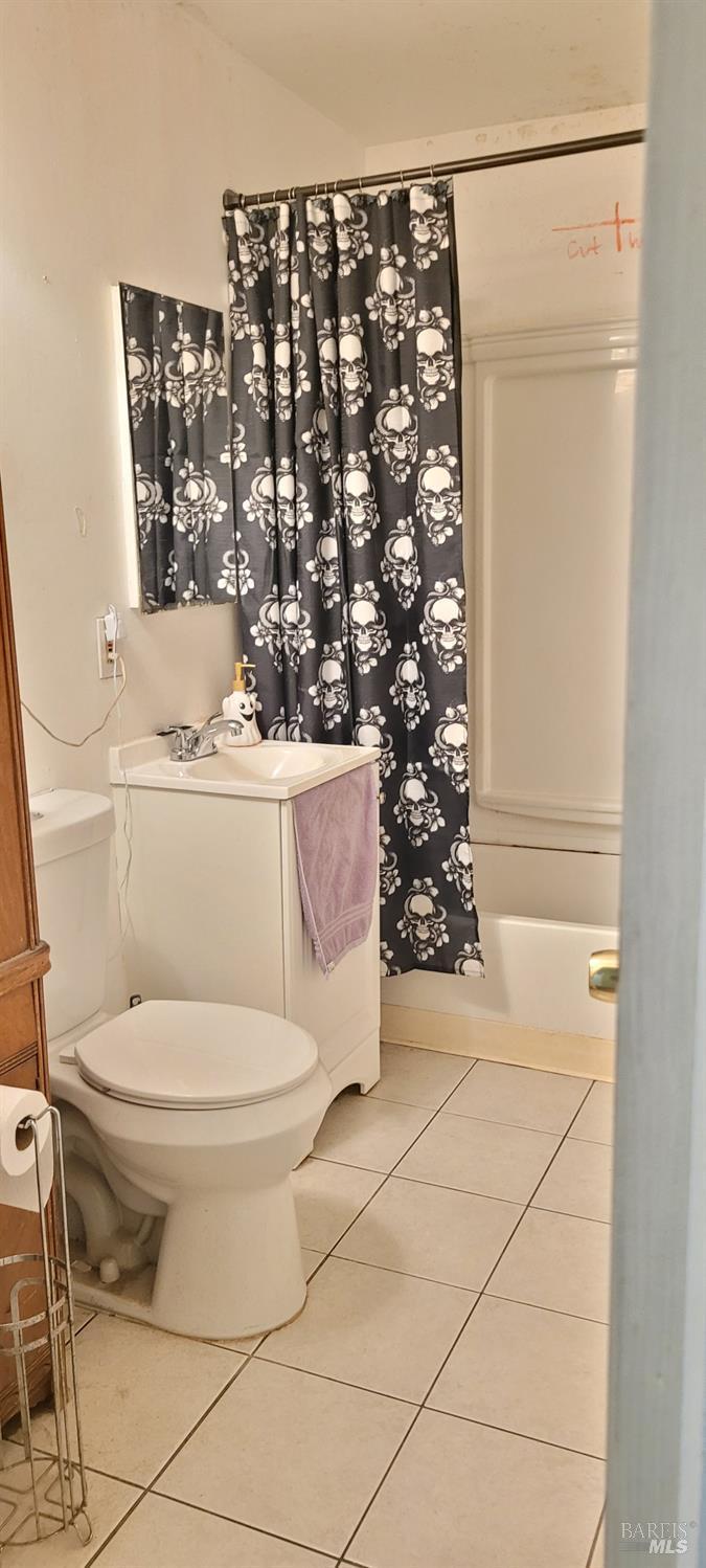 bathroom featuring tile patterned flooring, toilet, and shower / bath combo with shower curtain