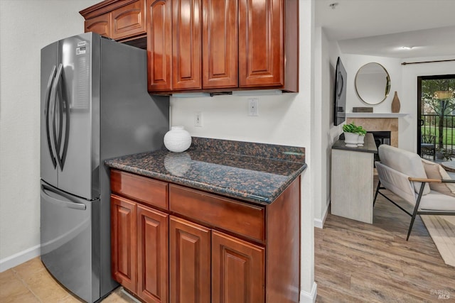 kitchen featuring dark stone counters, stainless steel refrigerator, and light hardwood / wood-style floors