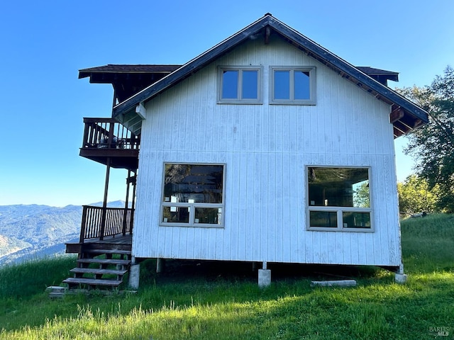 view of property exterior featuring a deck with mountain view and a lawn