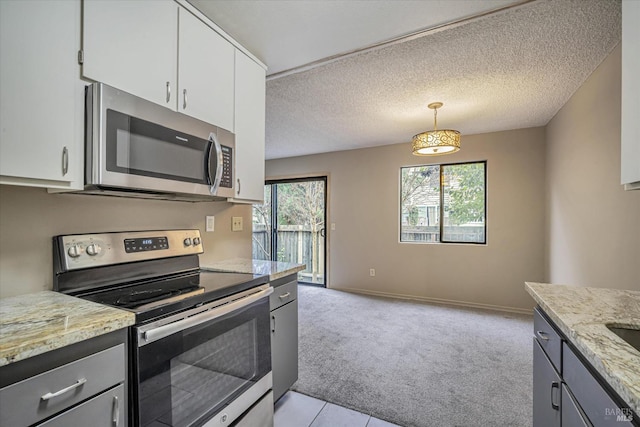 kitchen featuring light colored carpet, appliances with stainless steel finishes, hanging light fixtures, a textured ceiling, and white cabinetry