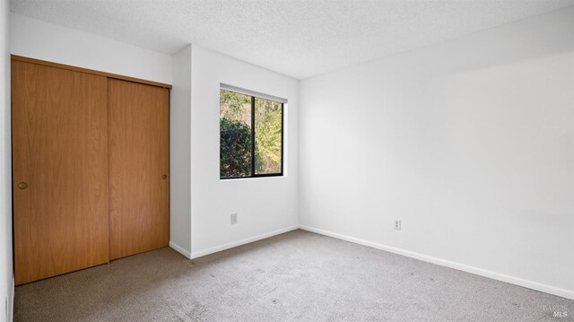 unfurnished bedroom with access to outside, carpet, baseboards, and a textured ceiling