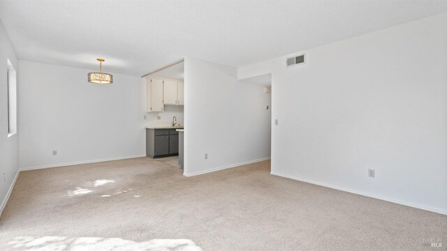 carpeted spare room with an inviting chandelier, a textured ceiling, and baseboards