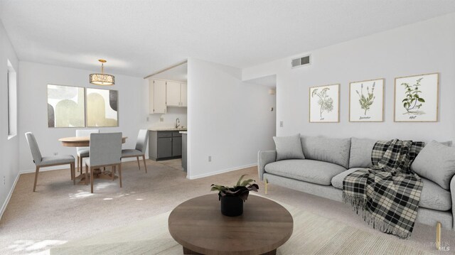 unfurnished living room with light colored carpet, a textured ceiling, and baseboards