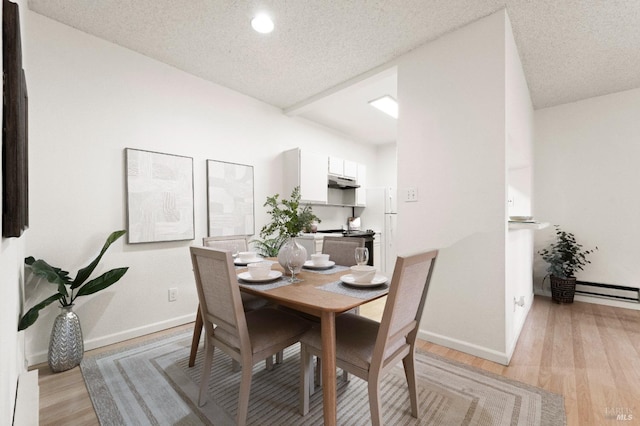 dining space featuring a textured ceiling and light wood-type flooring