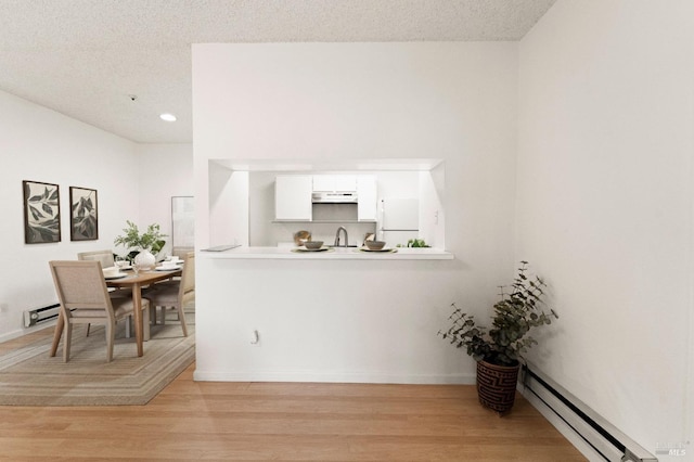 kitchen featuring sink, white cabinetry, white refrigerator, a baseboard radiator, and light hardwood / wood-style floors