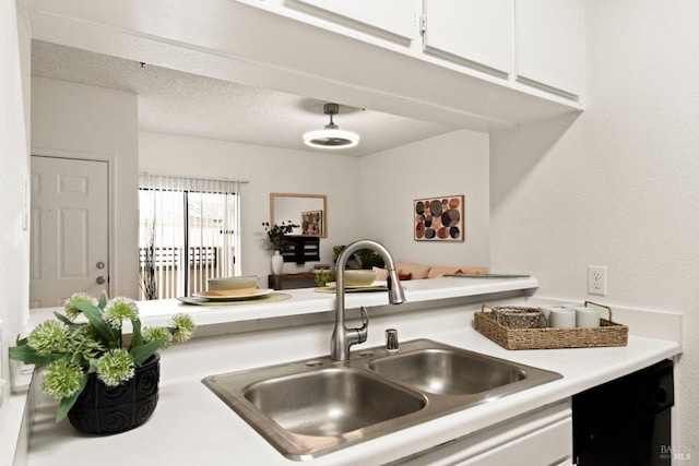 kitchen featuring black dishwasher, sink, a textured ceiling, and white cabinets