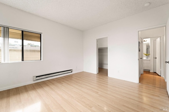 unfurnished bedroom with light wood-type flooring, a textured ceiling, and a baseboard heating unit