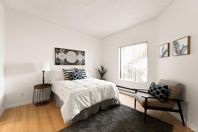 bedroom featuring a baseboard radiator, hardwood / wood-style floors, and a textured ceiling