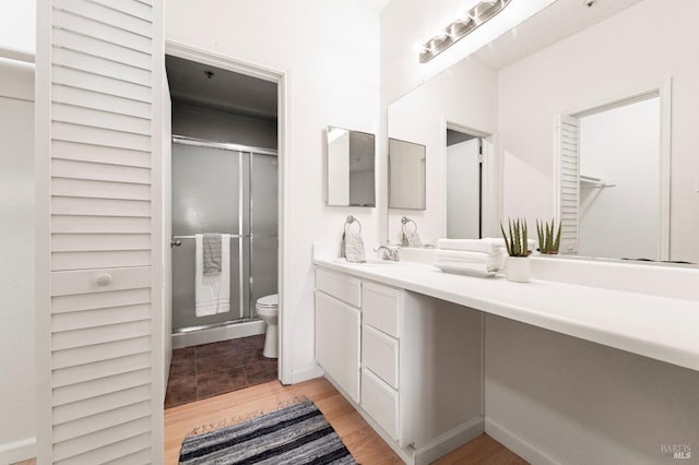 bathroom featuring vanity, hardwood / wood-style flooring, a shower with door, and toilet