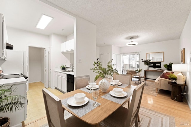 dining area with sink, light hardwood / wood-style floors, and a textured ceiling