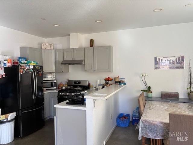 kitchen with stainless steel appliances, gray cabinets, a kitchen bar, and kitchen peninsula