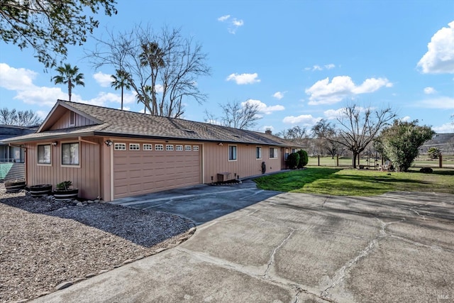 view of side of property featuring a garage, a yard, a shingled roof, and driveway