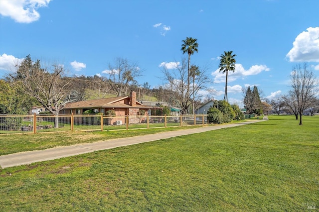 view of property's community with fence and a lawn