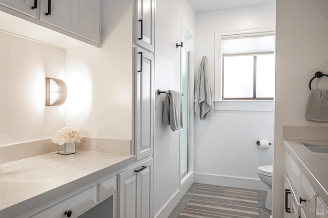 bathroom featuring a shower with door, vanity, and toilet