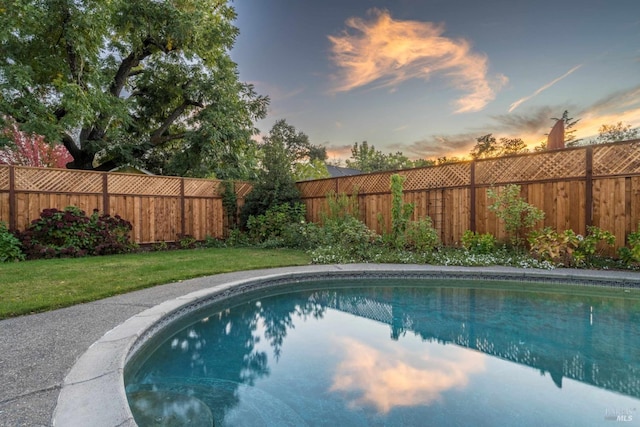 pool at dusk featuring a lawn