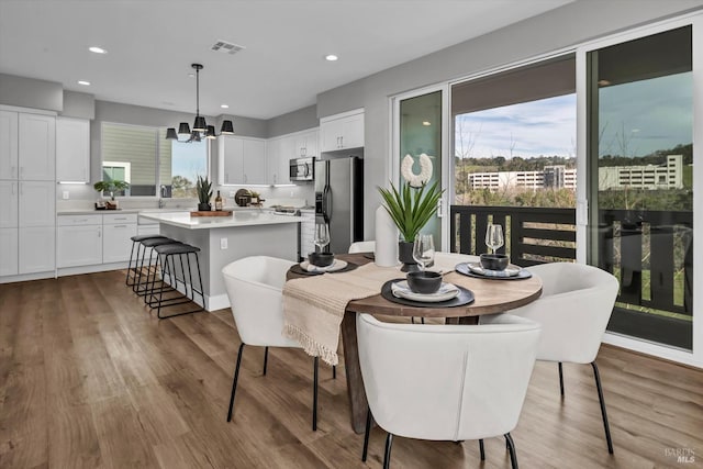 dining space with an inviting chandelier, a healthy amount of sunlight, and hardwood / wood-style flooring