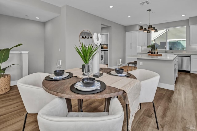 dining space with sink, a chandelier, and light wood-type flooring