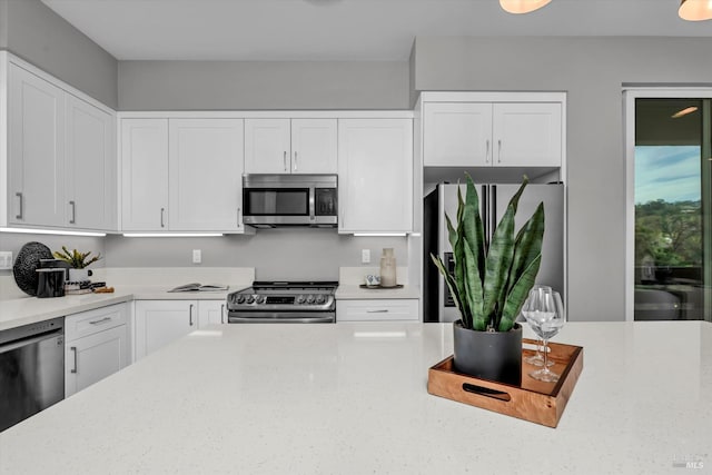 kitchen featuring white cabinetry, appliances with stainless steel finishes, and light stone counters