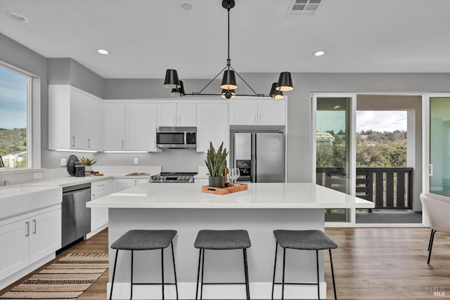 kitchen featuring pendant lighting, sink, appliances with stainless steel finishes, white cabinets, and a kitchen island