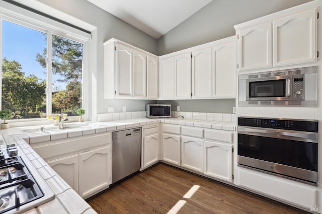 kitchen with stainless steel appliances, white cabinetry, a healthy amount of sunlight, and tile countertops