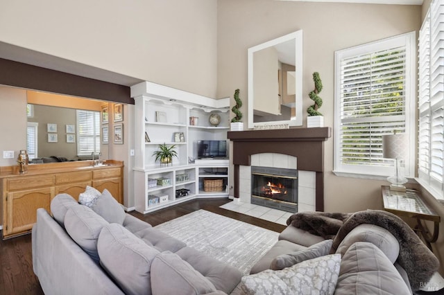 living room featuring dark hardwood / wood-style floors, a tiled fireplace, and sink