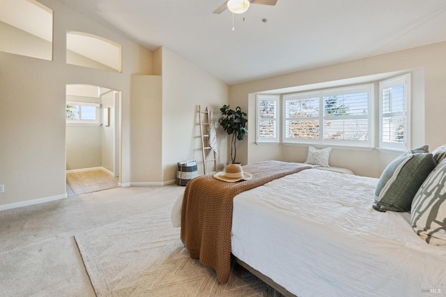 carpeted bedroom with ceiling fan, connected bathroom, and vaulted ceiling