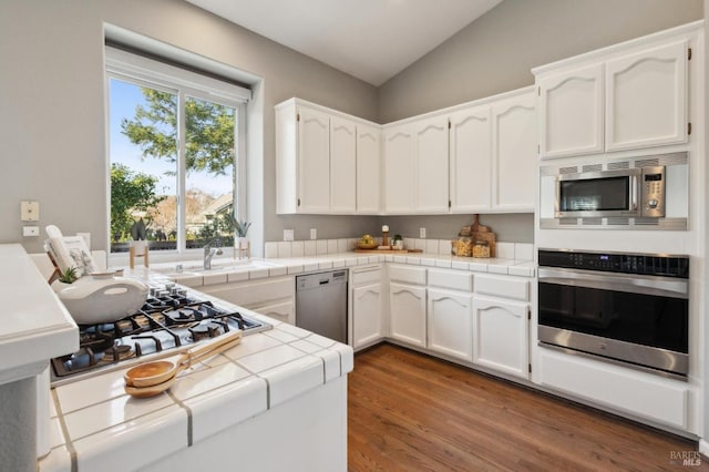 kitchen featuring tile countertops, stainless steel appliances, and white cabinets