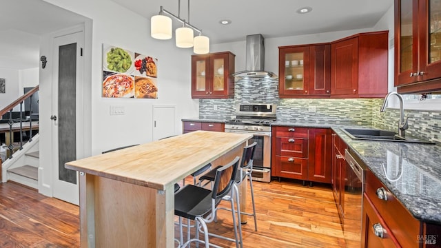 kitchen with pendant lighting, sink, a kitchen island, stainless steel range with gas cooktop, and wall chimney exhaust hood