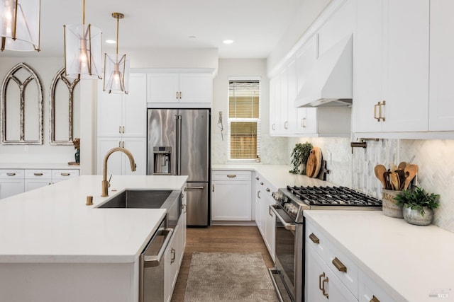 kitchen featuring premium range hood, sink, pendant lighting, stainless steel appliances, and a kitchen island with sink