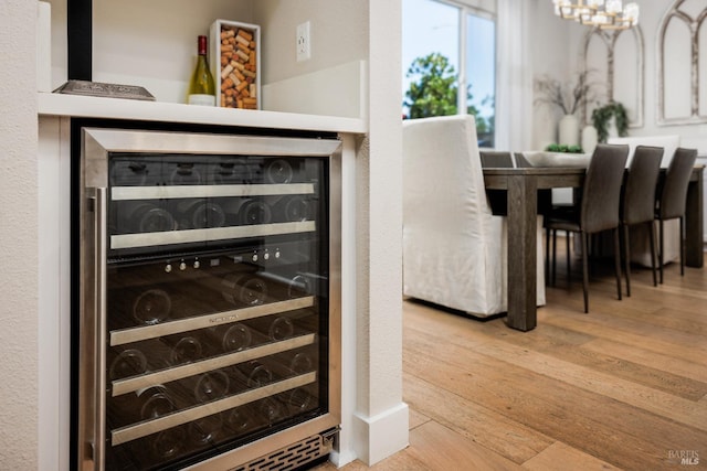 dining room with hardwood / wood-style floors, beverage cooler, and a chandelier