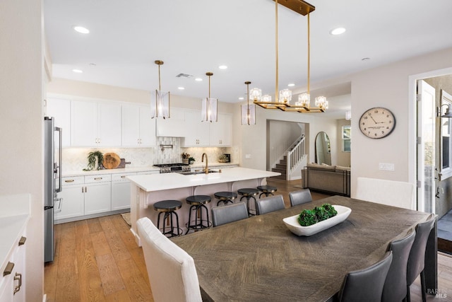 dining area with an inviting chandelier, sink, and light hardwood / wood-style flooring