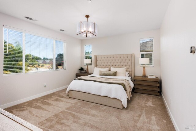 bedroom featuring multiple windows, light colored carpet, and an inviting chandelier