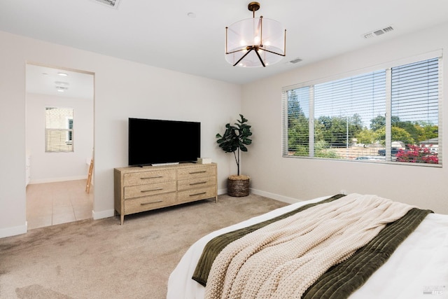 bedroom featuring an inviting chandelier and light colored carpet