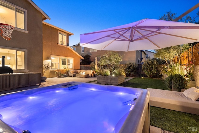 pool at dusk with an outdoor living space, a hot tub, and a patio area