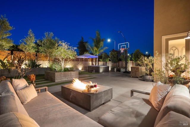 patio at twilight featuring an outdoor living space with a fire pit and a hot tub