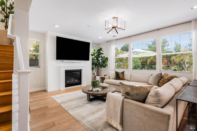 living room with a notable chandelier, plenty of natural light, and light wood-type flooring