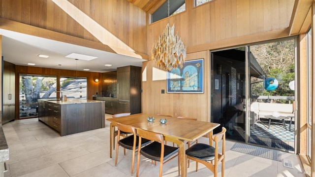 dining room with light tile patterned floors, a high ceiling, and wood walls