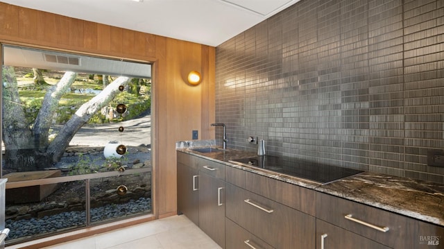 kitchen with light tile patterned flooring, sink, tasteful backsplash, dark stone countertops, and black electric stovetop