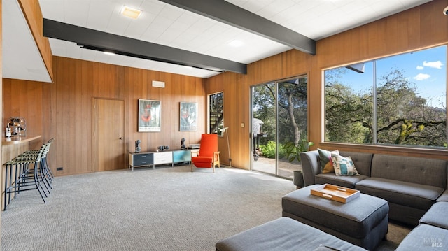 living room with carpet floors, wooden walls, and beamed ceiling