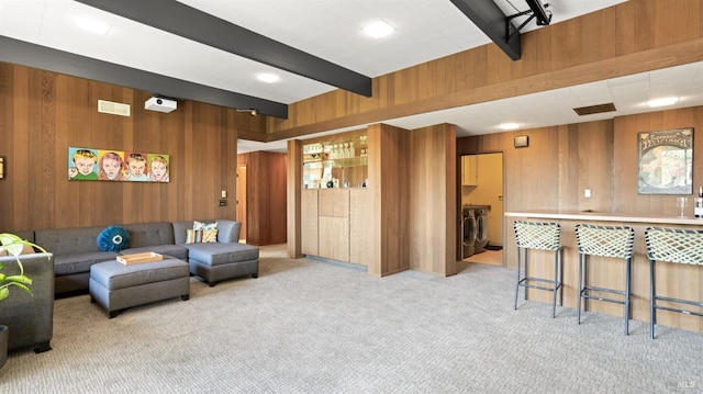 carpeted living room featuring beamed ceiling, separate washer and dryer, and wood walls