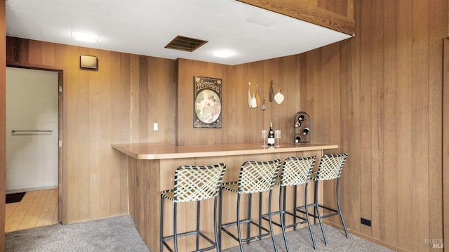 bar featuring light carpet and wooden walls